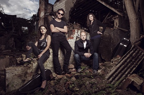 The quartet members, dressed in black, posed on the rubble of a ruined building