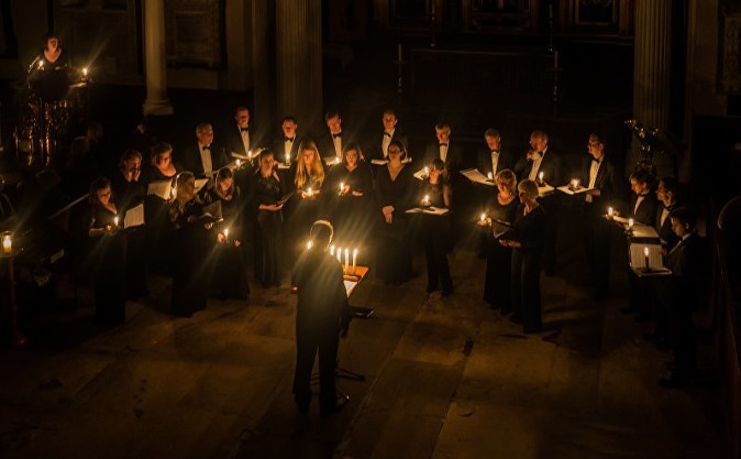 The choir viewed from above. The only lighting is from the candles that each singer is holding and those on the conductor's stand.