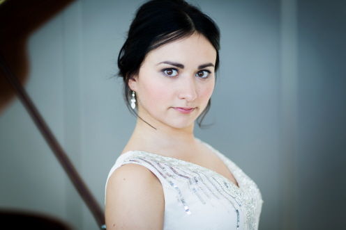 Three-quarter head and shoulders picture of Dinara. She is wearing a sleeveless white dress embellished with sequins