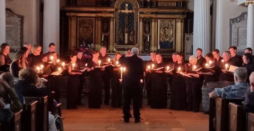 Jeffrey Skidmore conducting the choir at the 2022 concert. Each of the singers holds a lit candle to light their music; all other lighting is off