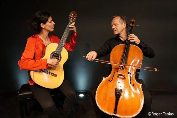 Nathalie Mengual and François Ragot, seated playing their guitar and cello against a dark background
