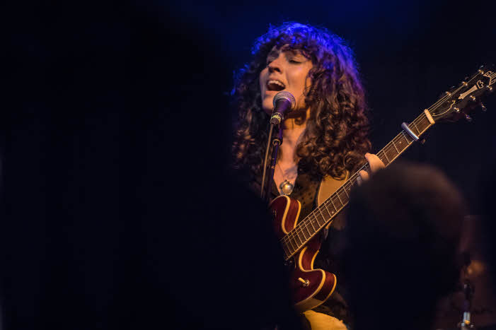 Hattie Whitehead, lead singer of Hejira, singing on stage with electric guitar.