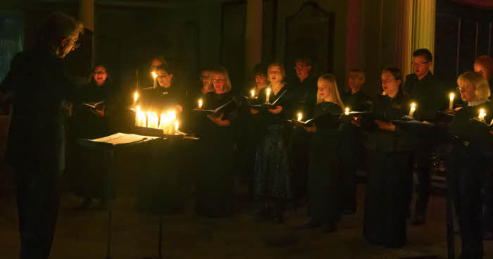 A section of the choir with their director, lit only by candlelight, at last year's concert.